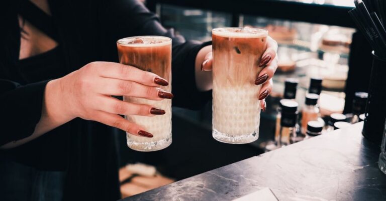 Cafes - Two people holding up two glasses of coffee