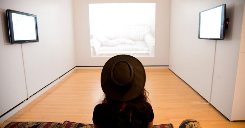 Museums - Woman Sitting on Red-and-green Suede Sofa Facing Well Lighted Room