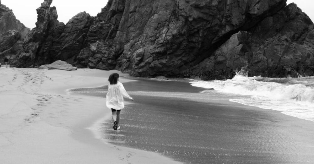 Trails - Woman Walking on Beach to Rock